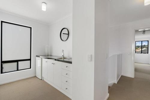 a white kitchen with a sink and a mirror at Lakehouse28 Waterfront Resort Living Encounter Bay - BYO Linen in Encounter Bay