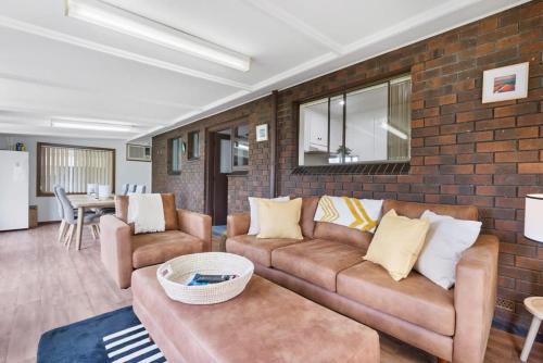 Goolwa Southにある58 Colman Rd Goolwa South - BYO Linenのソファとレンガの壁のあるリビングルーム