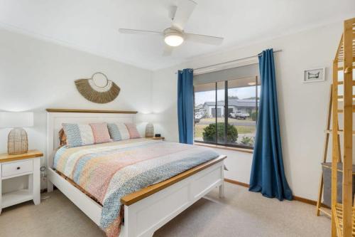 um quarto com uma cama com cortinas azuis e uma janela em 58 Colman Rd Goolwa South - BYO Linen em Goolwa South