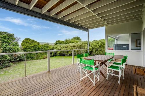 a deck with a wooden table and green chairs at 10 Passatt St Encounter Bay - BYO Linen in Encounter Bay