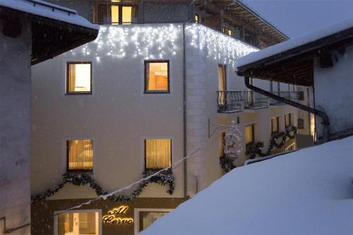 a building with snow on the side of it at Hotel Al Cervo in Tesero