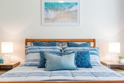 Bett mit blauer und weißer Bettwäsche und Kissen in der Unterkunft 13A Elliot Ave BYO Linen - SeaViews - Walk to Beach - Bikeway - Wi-Fi in Hayborough