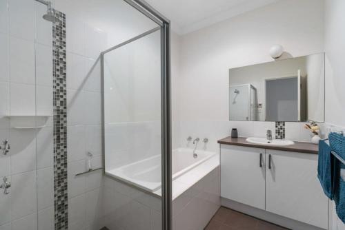 ein weißes Bad mit einer Dusche und einem Waschbecken in der Unterkunft 13A Elliot Ave BYO Linen - SeaViews - Walk to Beach - Bikeway - Wi-Fi in Hayborough