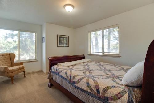 a bedroom with a bed and a chair and windows at Timber Creek Escape in Sisters