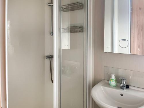 biała łazienka z prysznicem i umywalką w obiekcie Woodend Caravan w mieście Lairg