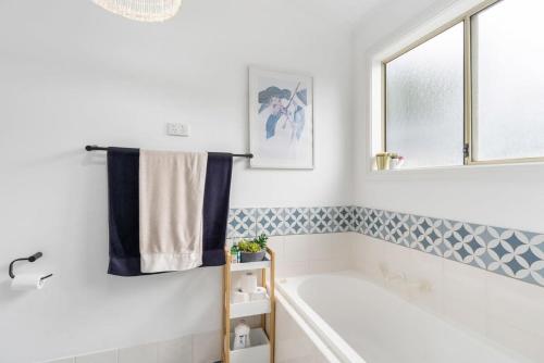 baño blanco con bañera y ventana en 32 Beach Rd Goolwa South-No Linen Included, en Goolwa South