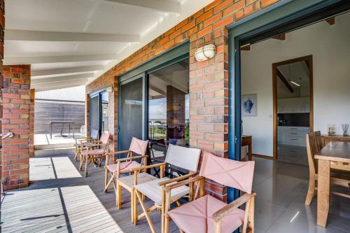 a patio with chairs and a brick wall at 20 Sir George Ritchie Ave Goolwa South - No Linen Included in Goolwa South