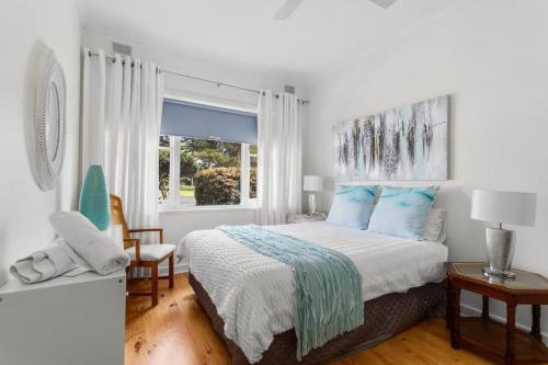 een slaapkamer met een bed met blauwe kussens en een raam bij 18 Strangways Tce Port Elliot - Linen Included in Port Elliot