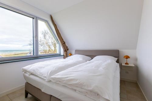 - une chambre avec un lit doté de draps blancs et une fenêtre dans l'établissement Haus ANNA, à Ahrenshoop