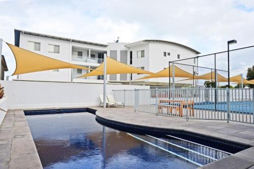 a pool with yellow umbrellas next to a building at Gallery 7 - Town Centre - Wi-Fi - Linen Included in Victor Harbor