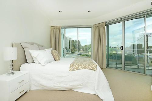 Un dormitorio con una cama blanca y una ventana grande. en Gallery 7 - Town Centre - Wi-Fi - Linen Included, en Victor Harbor