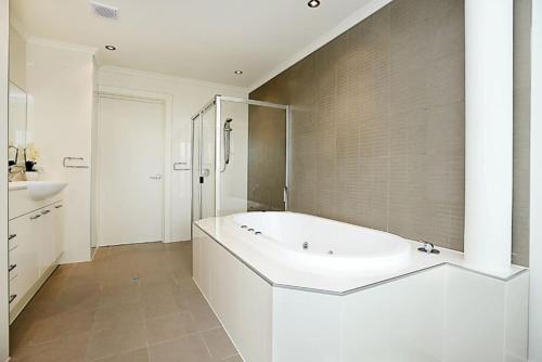 Un baño blanco con bañera y lavabo. en Gallery 7 - Town Centre - Wi-Fi - Linen Included, en Victor Harbor