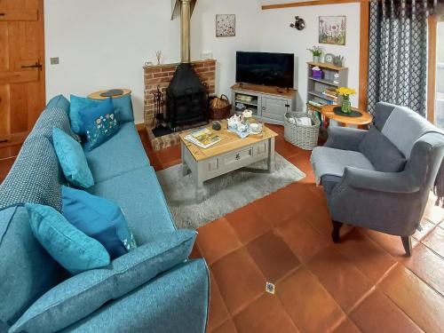 a living room with two blue couches and a fireplace at Meadow Barn in Wool