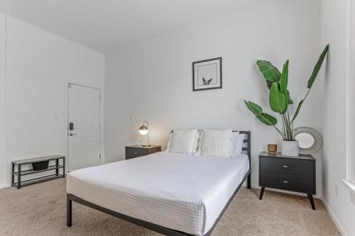 a white bedroom with a bed and a potted plant at Housepitality - The Short North Getaway in Columbus