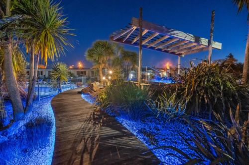 a pathway with palm trees and a building at night at Tasman Holiday Parks - Rotorua in Rotorua