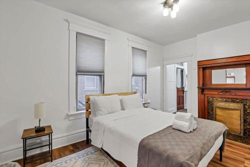 a white bedroom with a bed and a fireplace at Housepitality - The City Gateway in Columbus