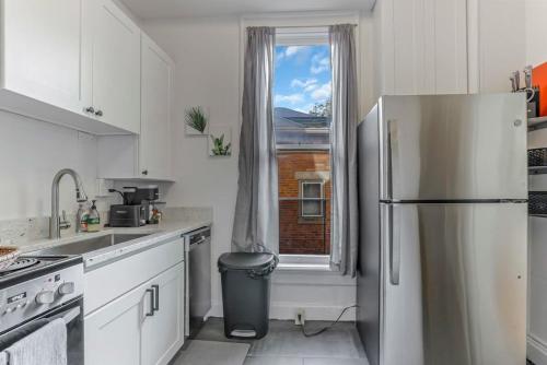 a white kitchen with a refrigerator and a window at Housepitality - The Short North Sanctuary in Columbus