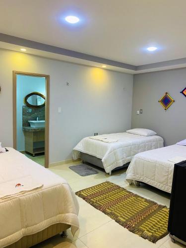 a room with two beds and a bathroom with a mirror at Hotel Alikaa Wayira in Ríohacha
