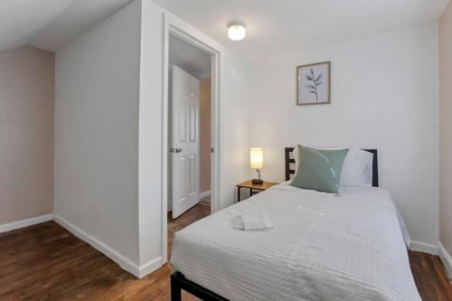 a white bedroom with a bed and a lamp at Housepitality - West Side Lodge - 6 BR 2 BA in Columbus