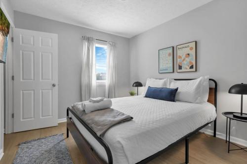 a white bedroom with a large bed with a window at The Schumacher Townhouse - 2 BR in Columbus
