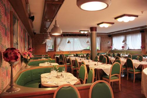 a restaurant with tables and chairs in a room at Hotel Majoni in Cortina dʼAmpezzo