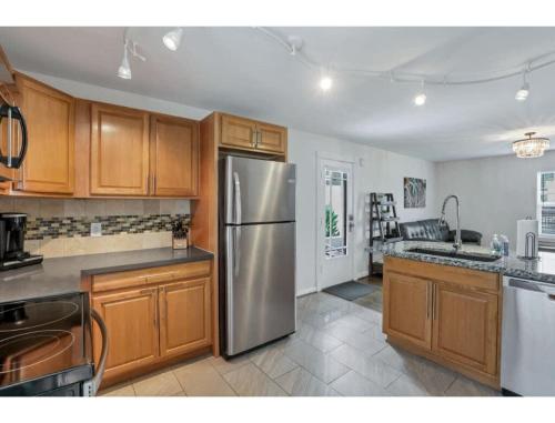 a kitchen with wooden cabinets and a stainless steel refrigerator at Housepitality - Little River Trails in Mason