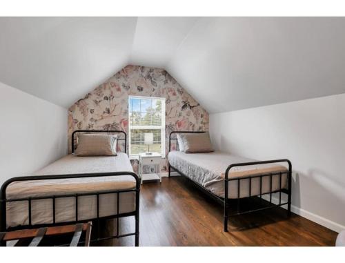two beds in a attic room with a window at Housepitality - Little River Trails in Mason