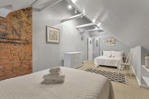 a white bedroom with a white bed and a brick wall at Housepitality - Harrison Mansion - Great Location in Columbus