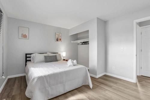 um quarto branco com uma grande cama branca e pisos em madeira em Housepitality - The Gahanna Ranch - 3 BR - Airport em Gahanna