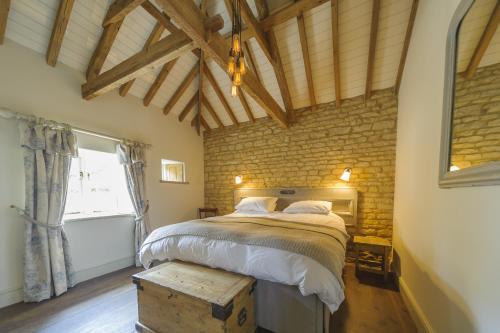 a bedroom with a large bed and a brick wall at Pea Cottage in Stamford