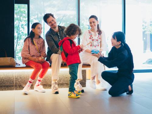 a group of people sitting on a bench playing with a child at MIMARU Kyoto Kawaramachi Gojo in Kyoto