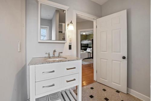 a white bathroom with a sink and a mirror at The Skyline Cottage - 3 BR Garage in Columbus