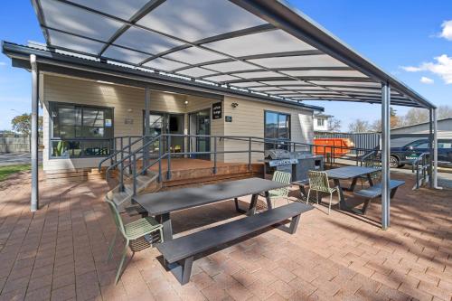 a patio with two picnic tables and awning at Tasman Holiday Parks - Rotorua in Rotorua