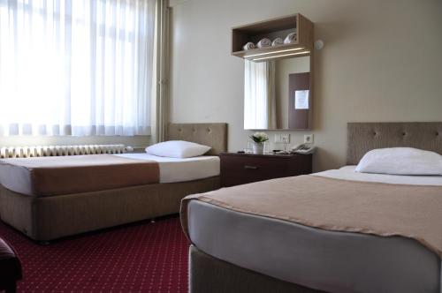 um quarto de hotel com duas camas e um espelho em Otel Sınal em Cocaeli