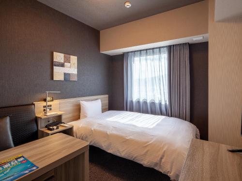 Hotel Route Inn Miyoshi Ekimae في Miyoshi: غرفه فندقيه بسرير ونافذه
