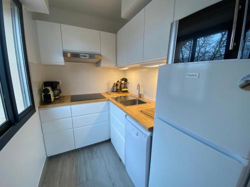 une cuisine avec des armoires blanches et un réfrigérateur blanc dans l'établissement Charmant T2 à Arcachon, accès direct plage, parking privé - FR-1-374-35, à Arcachon