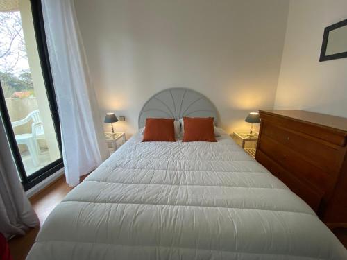 - une chambre avec un lit blanc et deux oreillers orange dans l'établissement Charmant T2 à Arcachon, accès direct plage, parking privé - FR-1-374-35, à Arcachon