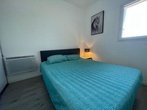 ein Schlafzimmer mit einem Bett mit blauer Decke und einem Fenster in der Unterkunft Appartement Argelès-sur-Mer, 3 pièces, 4 personnes - FR-1-309-422 in Argelès-sur-Mer