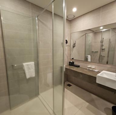 a bathroom with a glass shower and a sink at Hotel Nanta Jeju in Jeju