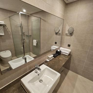 a bathroom with a sink and a toilet and a mirror at Hotel Nanta Jeju in Jeju