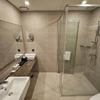 a bathroom with a shower and a sink at Hotel Nanta Jeju in Jeju