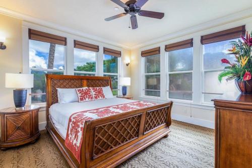 a bedroom with a bed and windows and a ceiling fan at E111 Ground Floor Poolside Patio in Koloa
