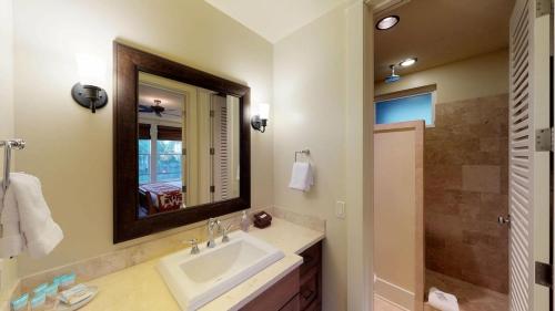 a bathroom with a sink and a mirror and a shower at D211 Second Floor 3-bedroom Poolside Lanai in Koloa