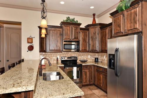 a kitchen with wooden cabinets and a stainless steel refrigerator at Coral Vista Suite Resort Pools BBQ Fireplace Jacuzzi Tub A9 in Washington