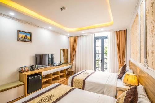 a hotel room with two beds and a television at Thành Đô Hotel Hạ Long in Ha Long