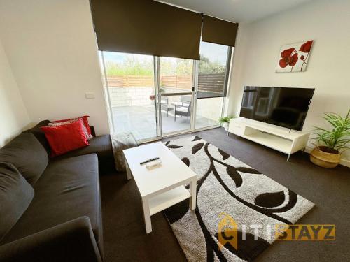 PhillipにあるWonder in Woden - 2 bd 2bth Aptのソファ、テレビ、テーブルのあるリビングルーム
