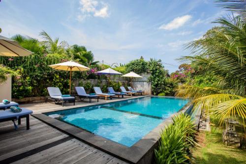 uma piscina com cadeiras e guarda-sóis num quintal em The Parnas em Nusa Lembongan