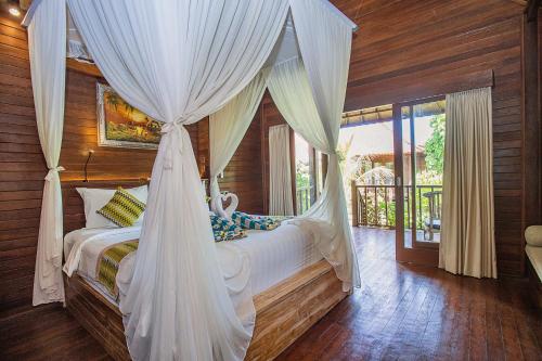 a bedroom with a bed with a canopy at The Parnas in Nusa Lembongan