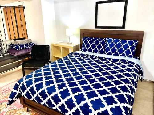 Un dormitorio con una cama azul y blanca y una silla en Manhattan in 2 stopages, 2 Bedrooms Apt with private Backyard in LIC !!!, en Long Island City