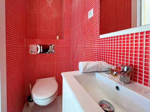uma casa de banho com azulejos vermelhos, um WC e um lavatório. em Stay U-nique Apartments Torrent em Barcelona